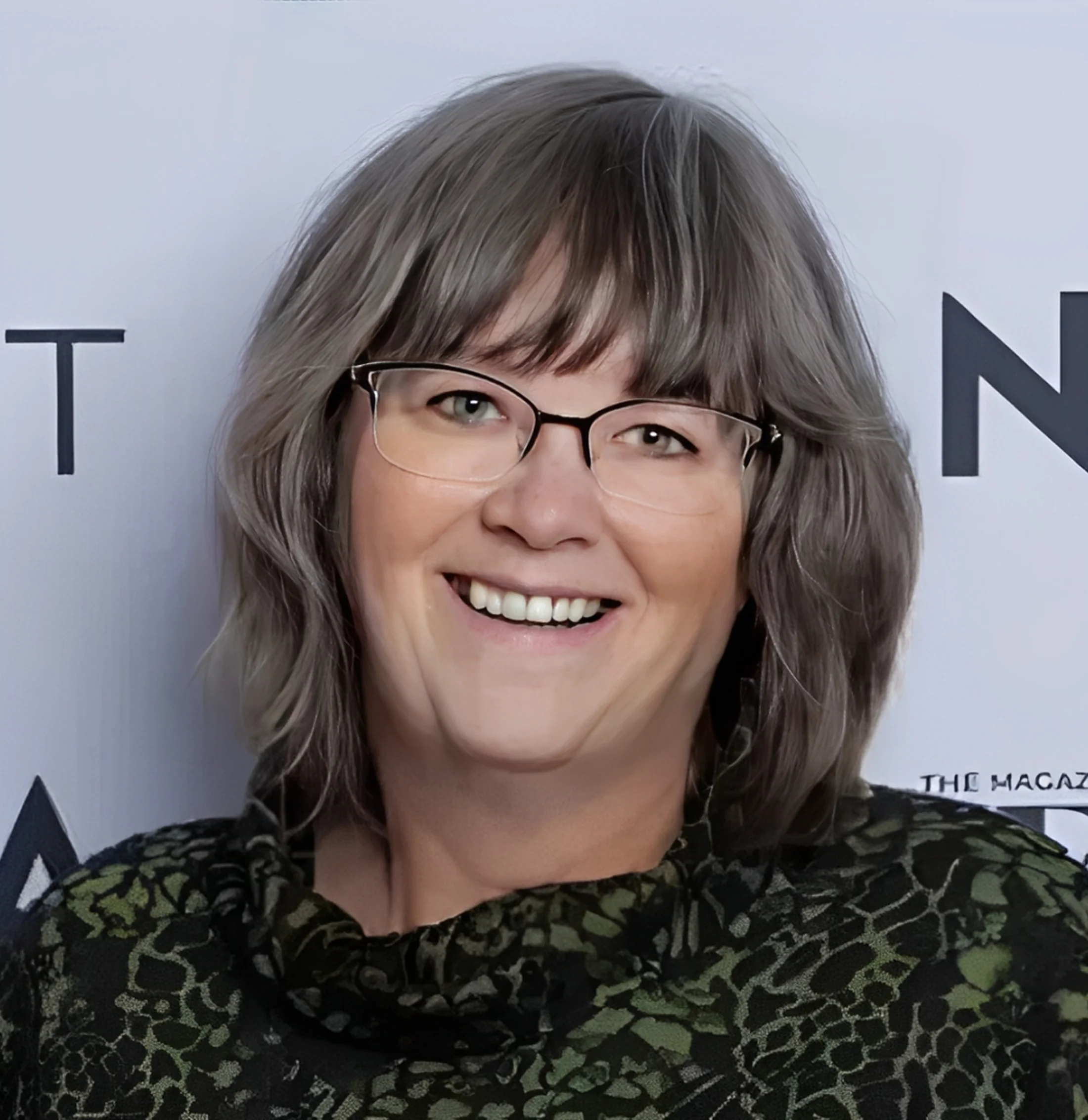 Smiling person with glasses and short hair.